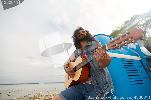 Image of hippie man playing guitar at minivan car outdoor