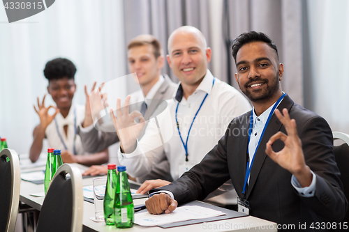 Image of people at business conference showing ok hand sign