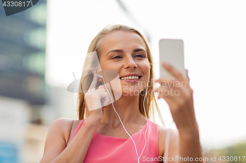 Image of happy young woman with smartphone and earphones