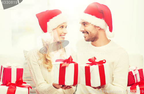 Image of happy couple at home exchanging christmas gifts