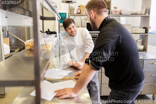 Image of chef and cook with grocery list at kitchen