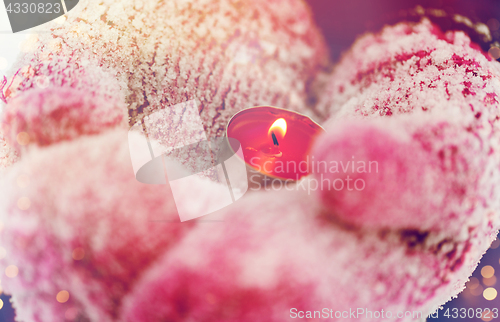 Image of close up of hands in winter mittens holding candle