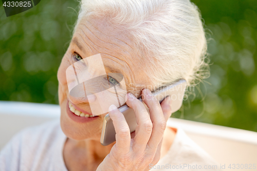 Image of happy senior woman calling on smartphone in summer