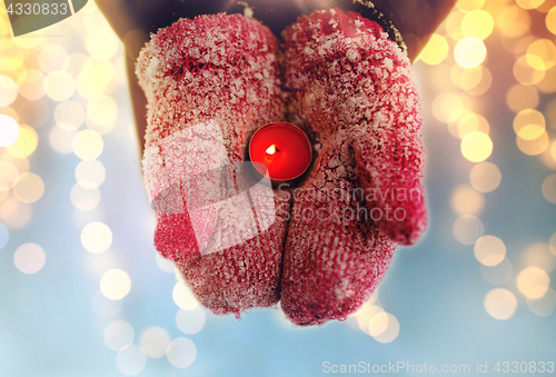 Image of close up of hands in winter mittens holding candle