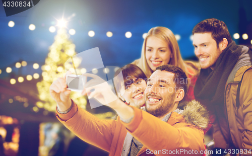 Image of happy friends with camera taking christmas selfie