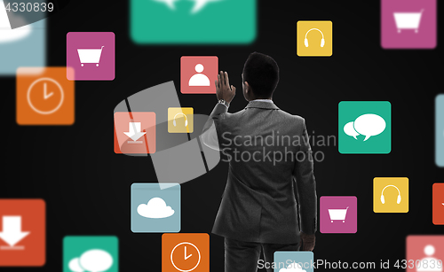 Image of businessman working with virtual icons over black