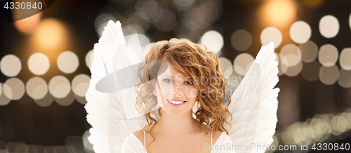 Image of happy woman with angel wings over christmas lights