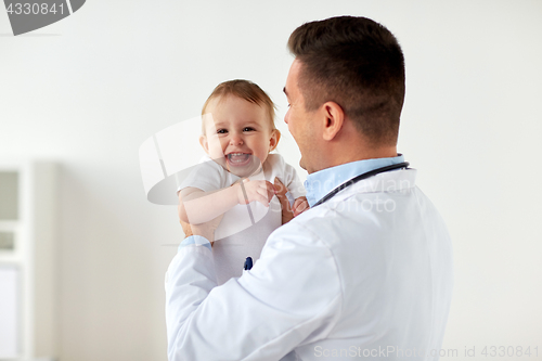 Image of happy doctor or pediatrician with baby at clinic