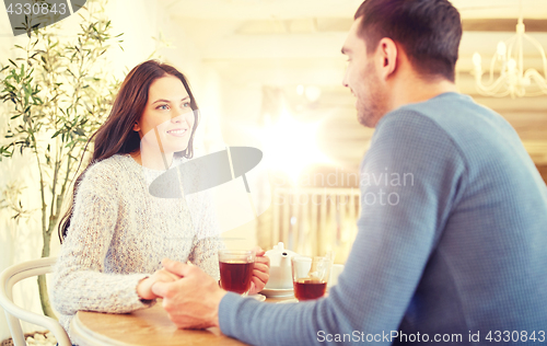 Image of happy couple with tea holding hands at restaurant