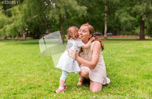 Image of happy mother hugging baby girl at summer park