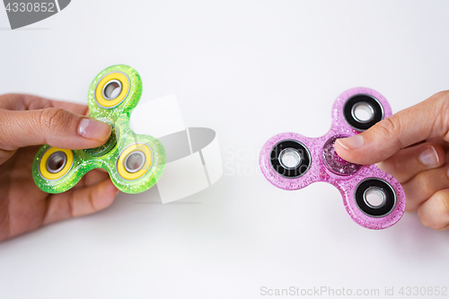 Image of close up of two hands playing with fidget spinners