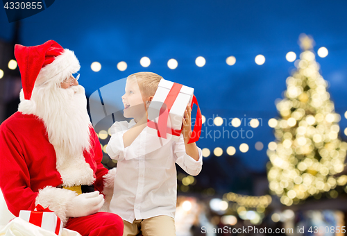 Image of santa claus and happy boy with christmas gift