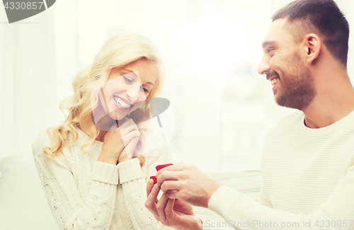 Image of happy man giving engagement ring to woman at home