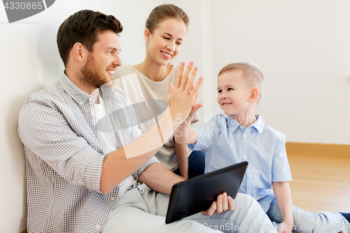 Image of family with tablet pc at new home making high five