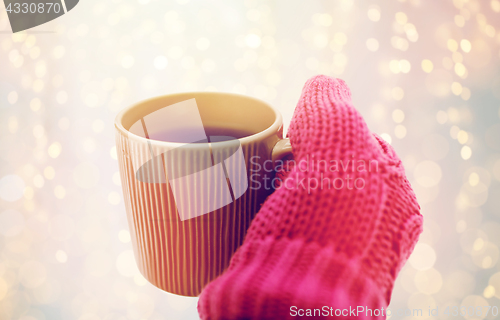 Image of close up of hand in winter mitten holding tea mug