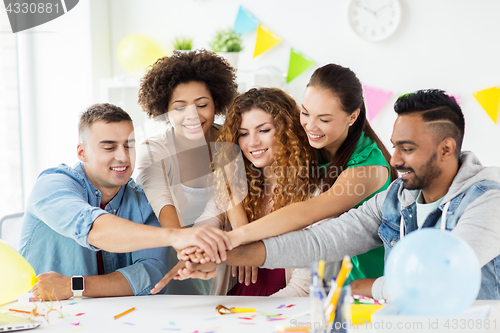 Image of happy team at office party holding hands together