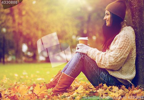 Image of close up of woman drinking coffee in autumn park