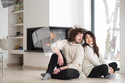 Image of happy multiethnic couple  in front of fireplace