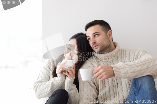 Image of multiethnic couple enjoying morning coffee by the window