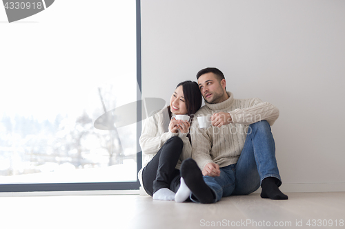 Image of multiethnic couple enjoying morning coffee by the window