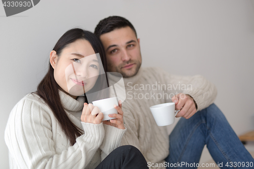 Image of multiethnic couple enjoying morning coffee by the window