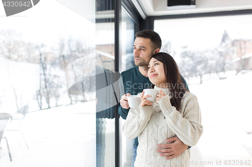 Image of multiethnic couple enjoying morning coffee by the window