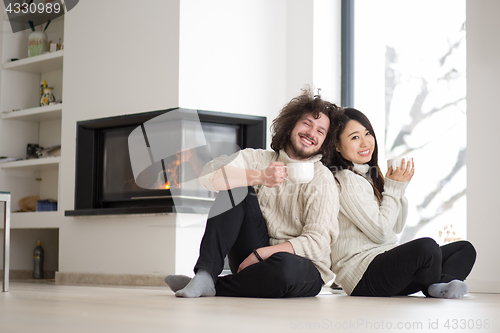 Image of happy multiethnic couple  in front of fireplace