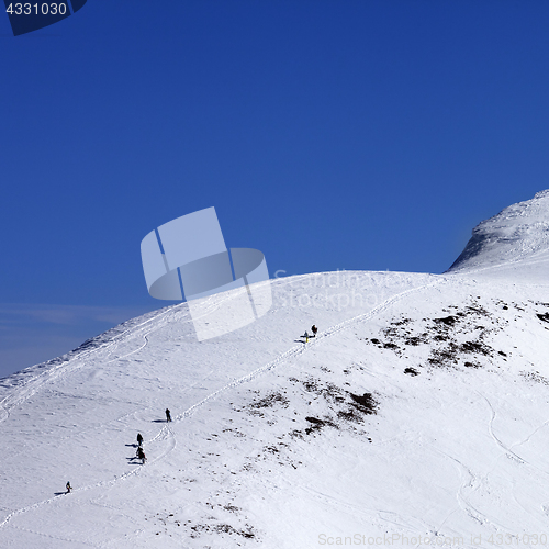 Image of Snowboarders and skiers downhill on off piste slope at sun day