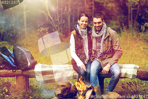 Image of happy couple sitting on bench near camp fire