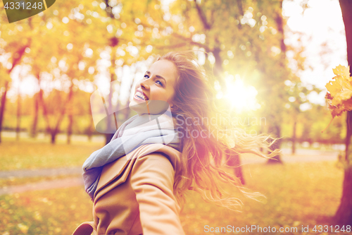 Image of beautiful happy young woman walking in autumn park