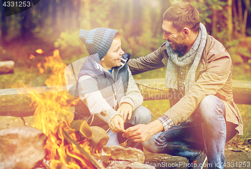 Image of father and son roasting marshmallow over campfire