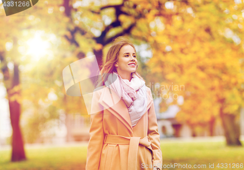 Image of beautiful happy young woman walking in autumn park