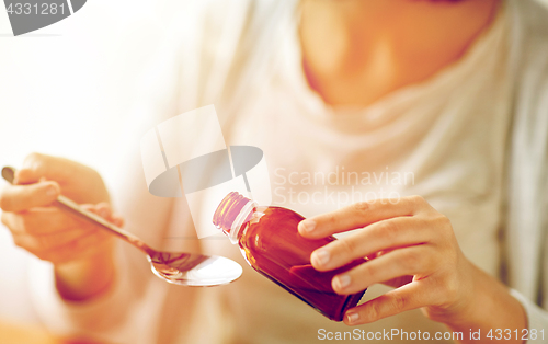 Image of woman pouring medicine from bottle to spoon