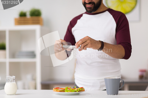 Image of man photographing food by smartphone at home