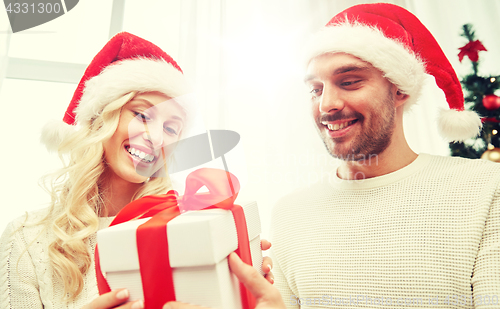 Image of happy couple at home with christmas gift box