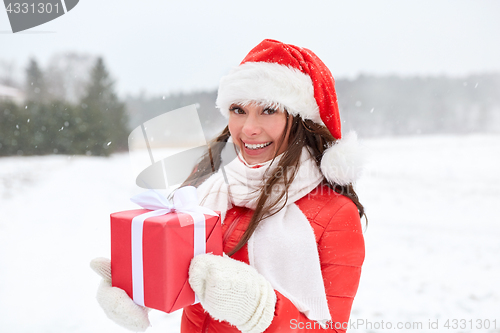 Image of happy woman in santa hat with chrismas gift