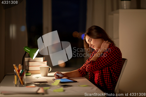 Image of tired student or woman touching neck at night home