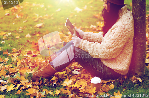 Image of woman with tablet pc and coffee in autumn park