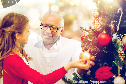 Image of grandfather and granddaughter at christmas tree