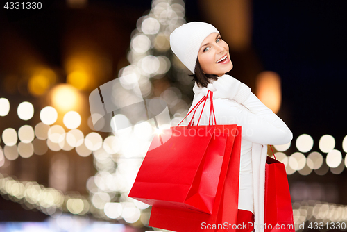 Image of happy woman with shopping bags over christmas tree