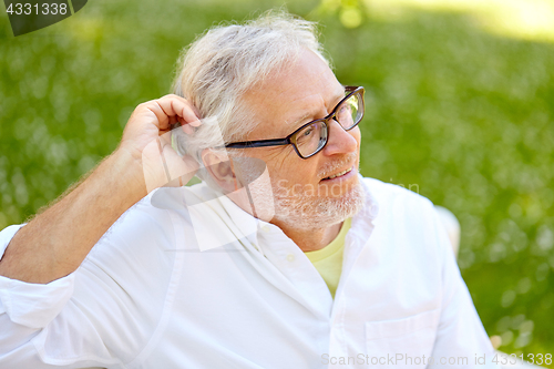 Image of happy senior man in glasses sitting at summer park