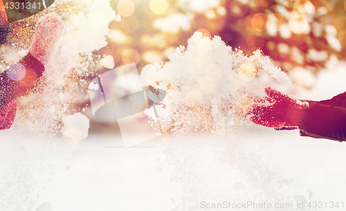 Image of happy friends playing with snow in winter