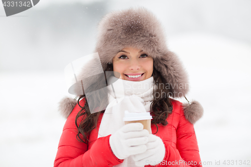 Image of happy woman in winter fur hat with coffee outdoors
