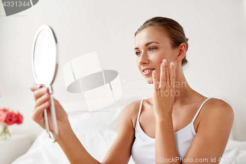 Image of beautiful woman with mirror sitting on bed at home