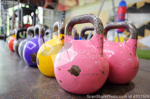 Image of colorful kettlebells in a row in a gym