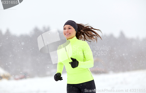 Image of happy woman running along snow covered winter road