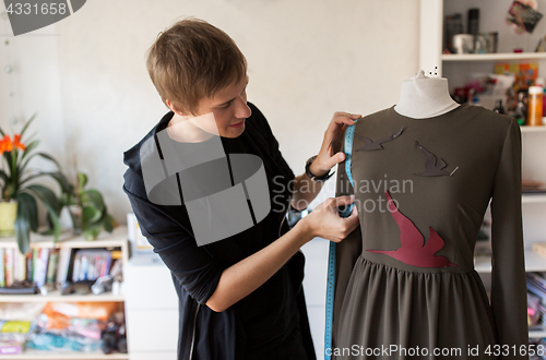 Image of fashion designer with dummy making dress at studio