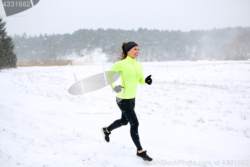 Image of happy woman running along snow covered winter road