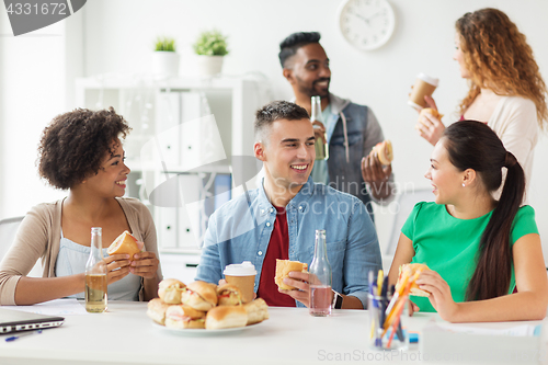 Image of happy friends or team eating at office party