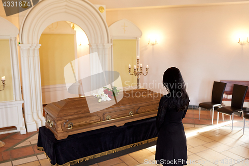 Image of sad woman with coffin at funeral in church